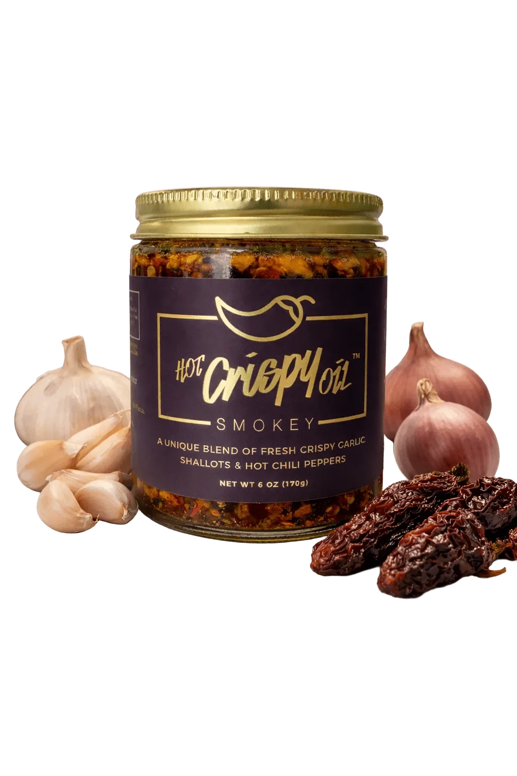 A jar of Hot Crepy Oil Smokey chili oil surrounded by fresh ingredients including garlic cloves, whole garlic bulbs, and dried red chilies on a white background.
