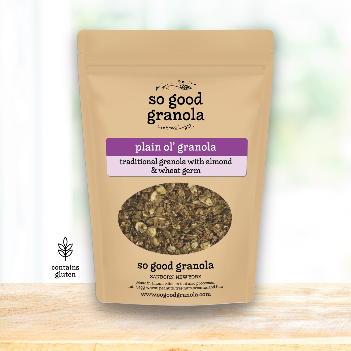 Kraft paper packaging of 'so good granola' with a clear window showing the granola inside.
